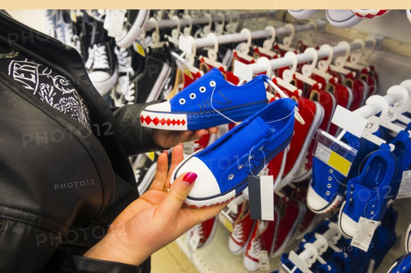 Hands of Caucasian woman holding sneakers in store