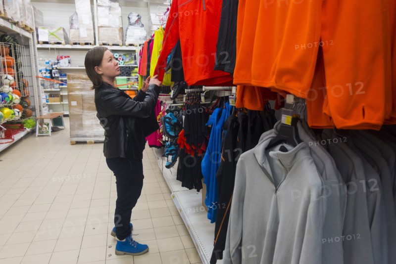 Caucasian woman examining shirt in store
