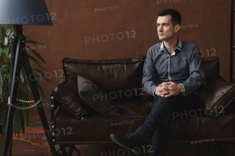 Pensive Middle Eastern man sitting on sofa