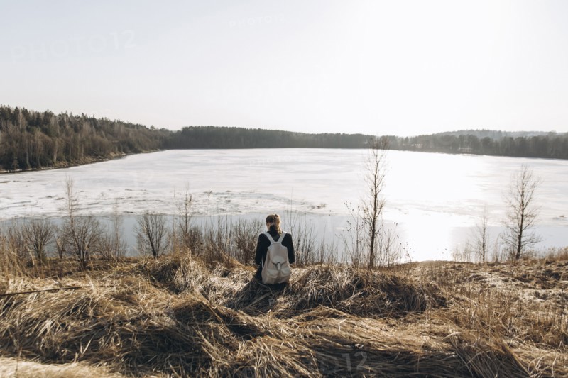 Middle Eastern woman sitting in grass near lake