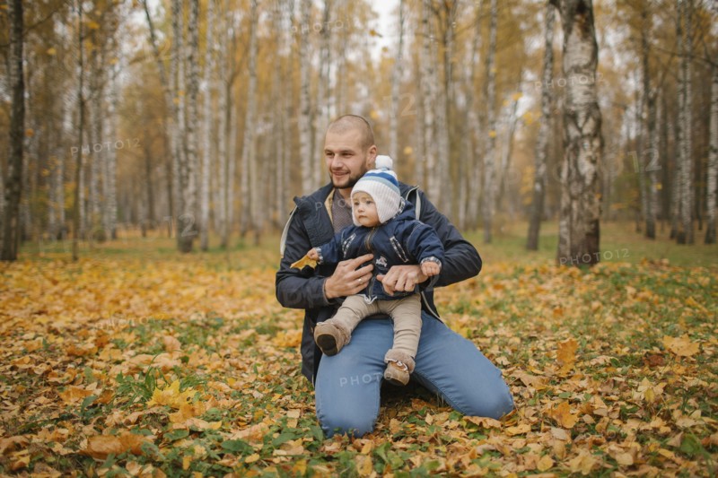 Middle Eastern father kneeling in park with baby son in autumn