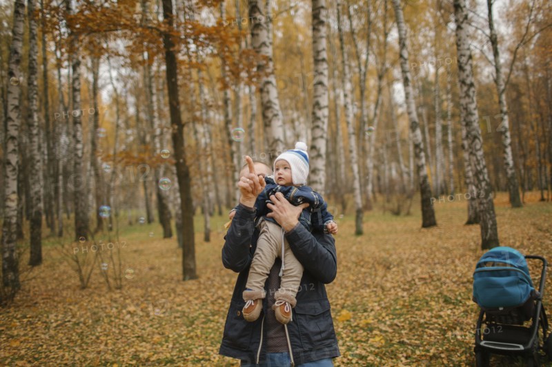 Middle Eastern father holding baby son and pointing in autumn