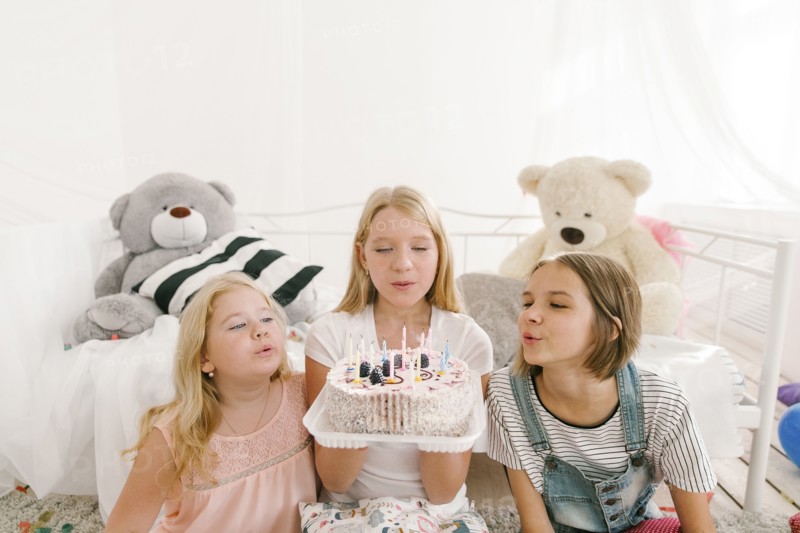 Middle Eastern sisters extinguishing candles on birthday cake