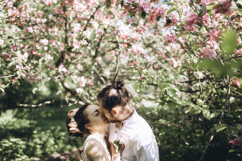 Middle Eastern couple kissing under flowering tree