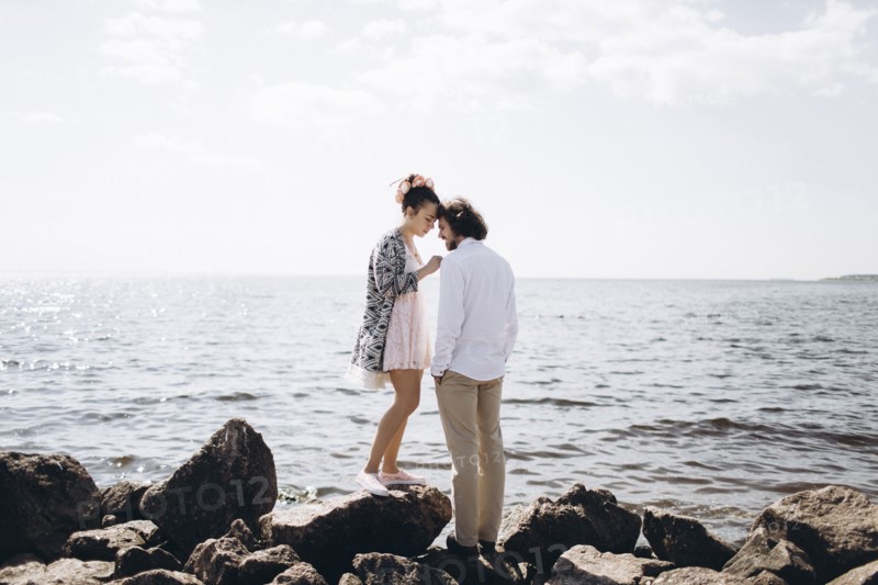 Middle Eastern couple standing on rocks near ocean