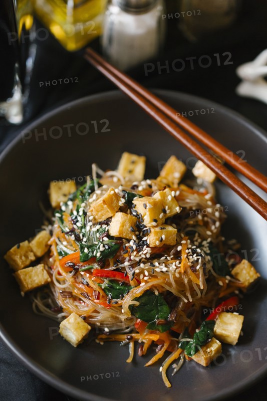 Chopsticks on bowl with noodles and tofu