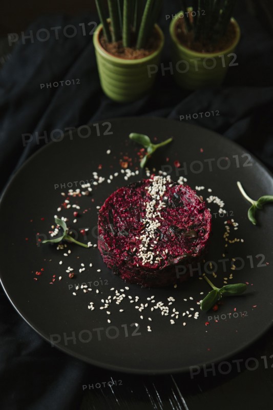 Sesame seeds and garnish on red food on plate