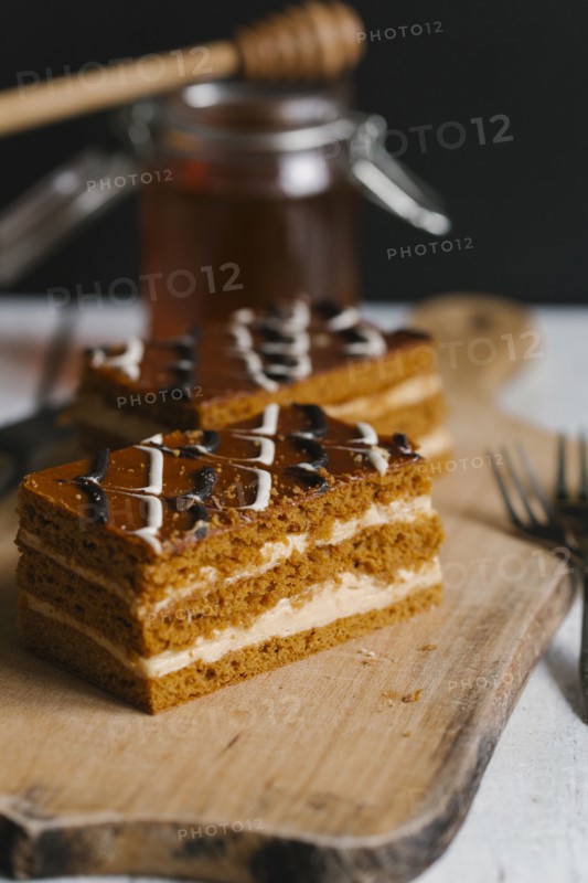 Slices of layer cake on cutting board with honey
