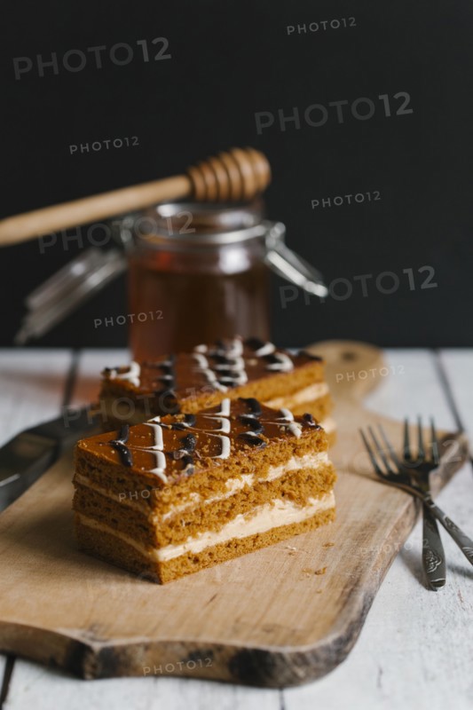 Slices of layer cake on cutting board with honey