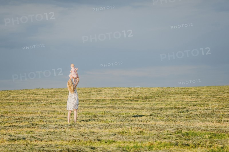 Mother lifting baby daughter in field