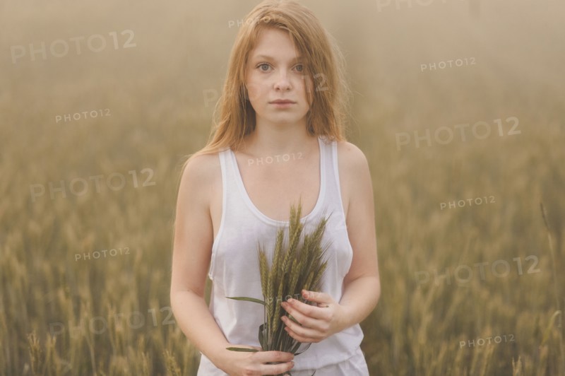 Middle Eastern teenage girl holding wheat in field