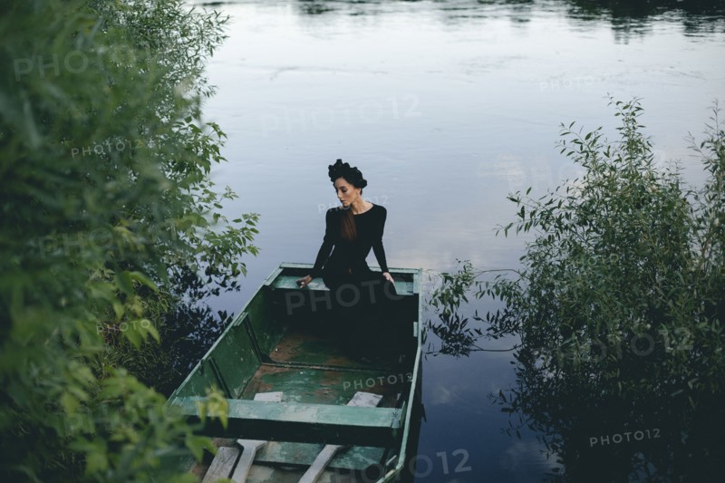 Middle Eastern woman wearing black dress in boat on lake