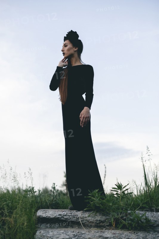 Middle Eastern woman wearing black dress standing on stone