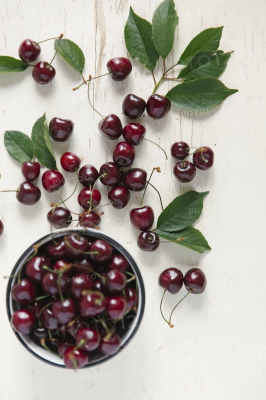 Cherries and bowl on white wooden table
