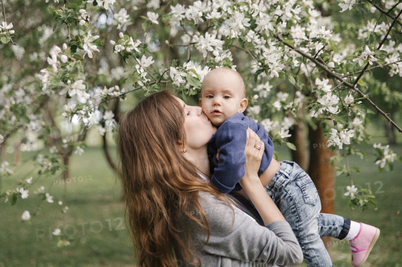 Middle eastern mother kissing son under flowering tree