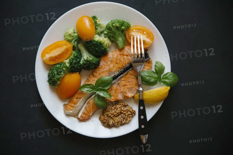 Cooked salmon on plate with broccoli and tomatoes