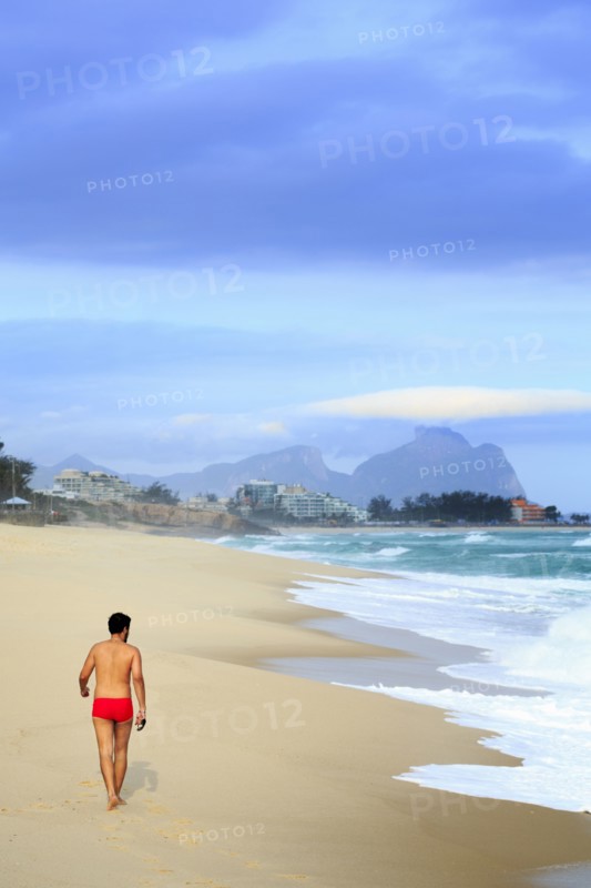 Hispanic man walking on beach near waves