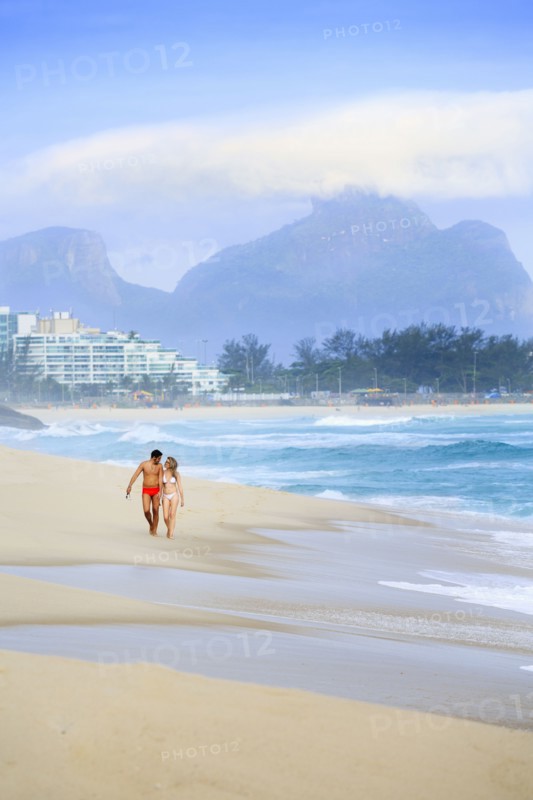 Couple walking on beach near waves