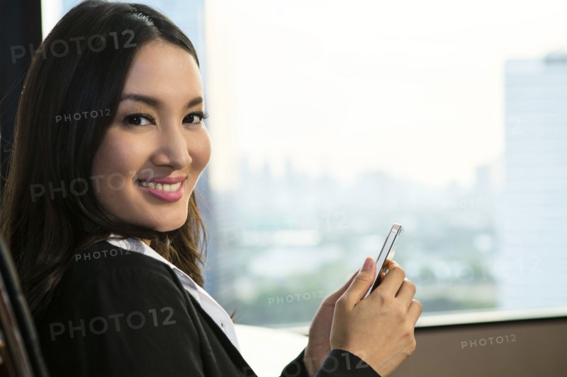 smiling Asian businesswoman texting on cell phone