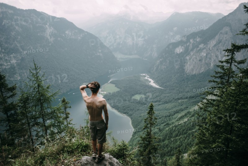 Caucasian man standing on rock overlooking lake in valley