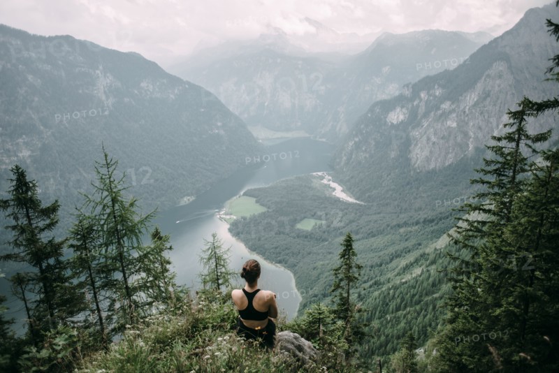 Caucasian woman sitting on rock overlooking lake in valley