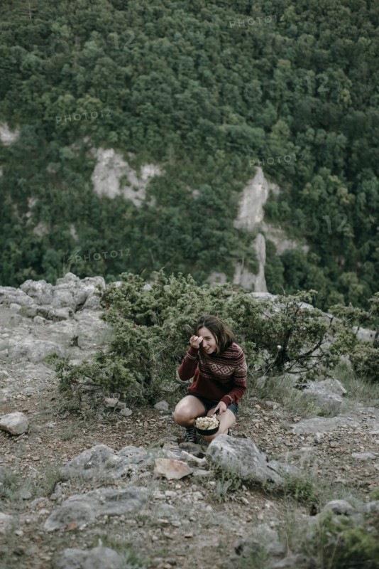 Smiling Caucasian woman crouching on mountain holding pan