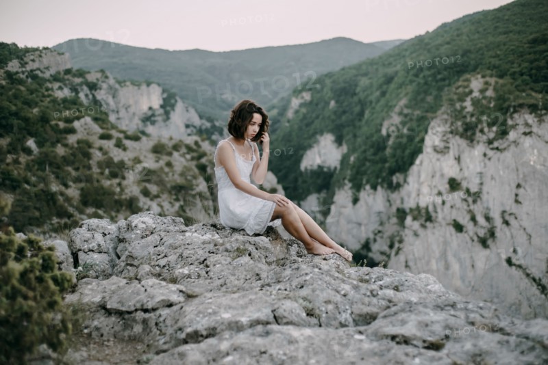 Pensive Caucasian woman sitting on mountain