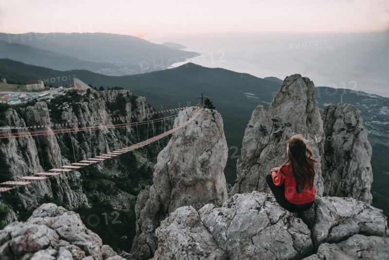 Caucasian woman sitting on mountain near footbridge