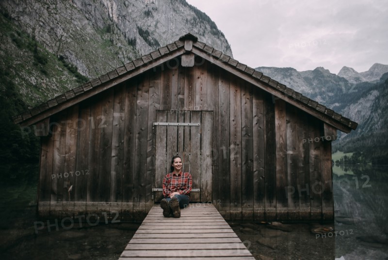 Caucasian woman sitting on dock at remote cabin