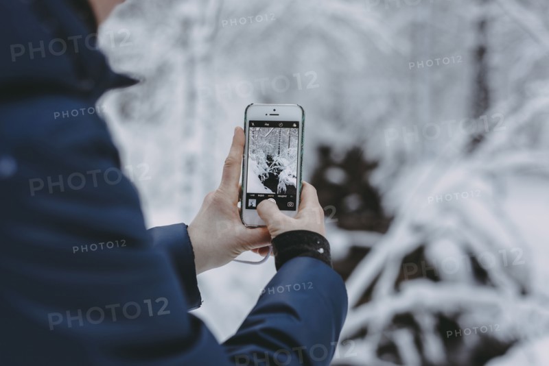 Caucasian woman photographing snow with cell phone