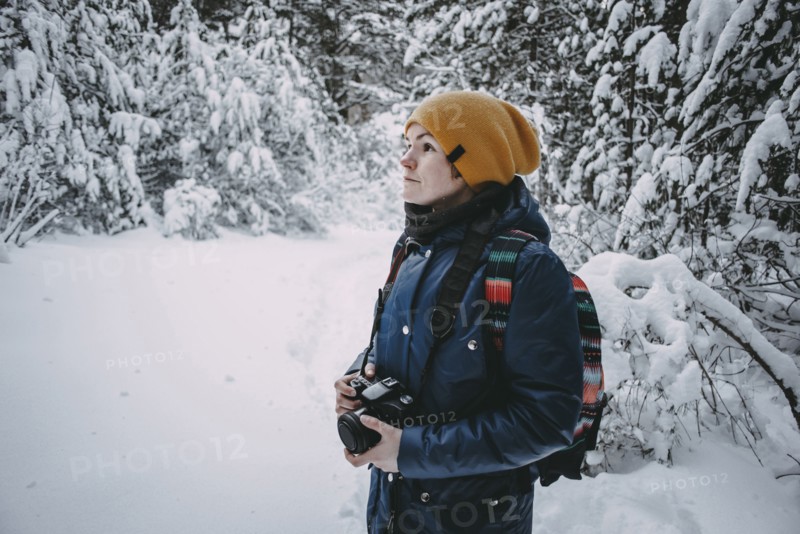 Caucasian woman holding camera in snowy forest
