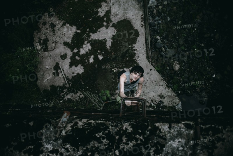 Caucasian man climbing ladder in concrete alley