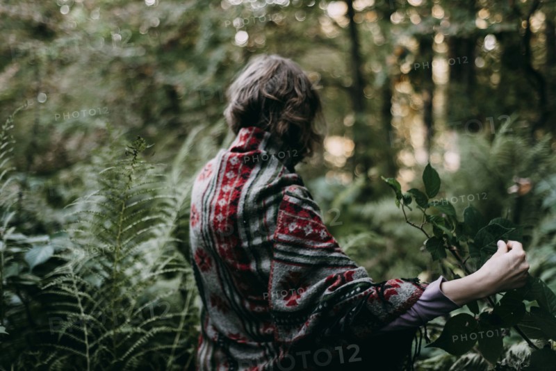 Caucasian woman holding green leaf in forest