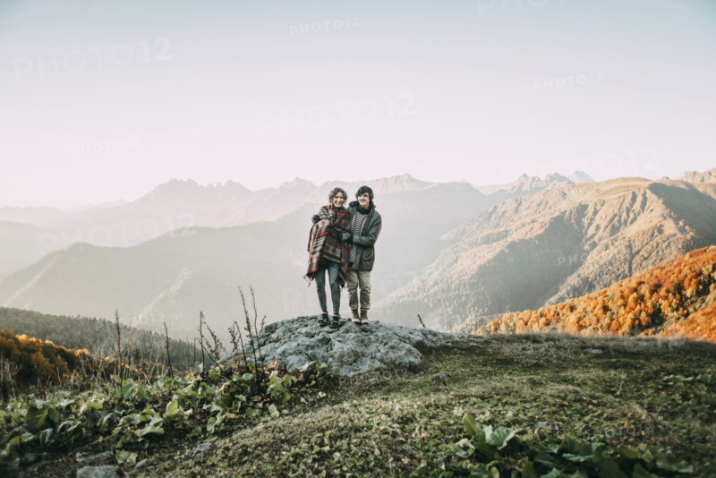 Caucasian couple standing on mountain rock overlooking valley