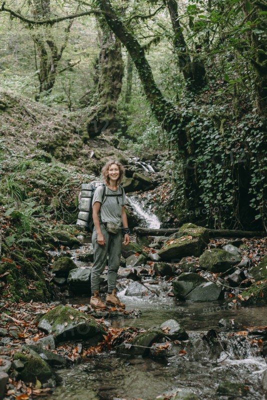 Caucasian woman backpacking across forest stream