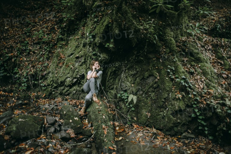Caucasian woman sitting in forest holding branch