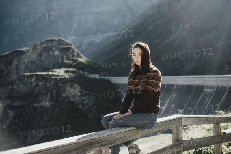 Pensive Caucasian woman sitting on wooden fence