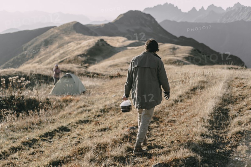 Caucasian man carrying bucket of snow to tent on mountain
