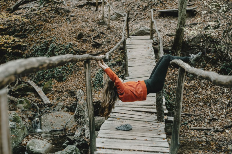 Caucasian woman playing on footbridge in woods