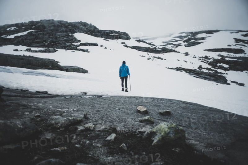Distant Caucasian man hiking in winter