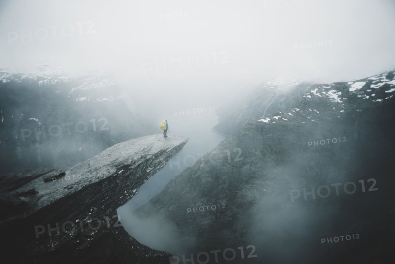 Caucasian man on foggy cliff admiring scenic view of mountain river