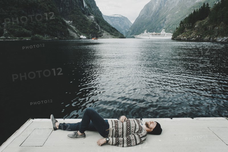 Caucasian man laying on dock at waterfront