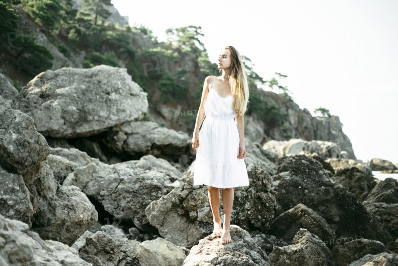 Caucasian woman wearing dress standing on rocks