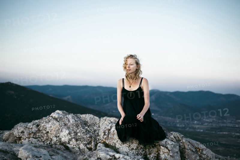 Caucasian woman sitting on rock near mountains