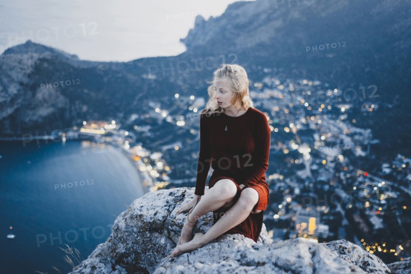 Caucasian woman sitting on rock near ocean