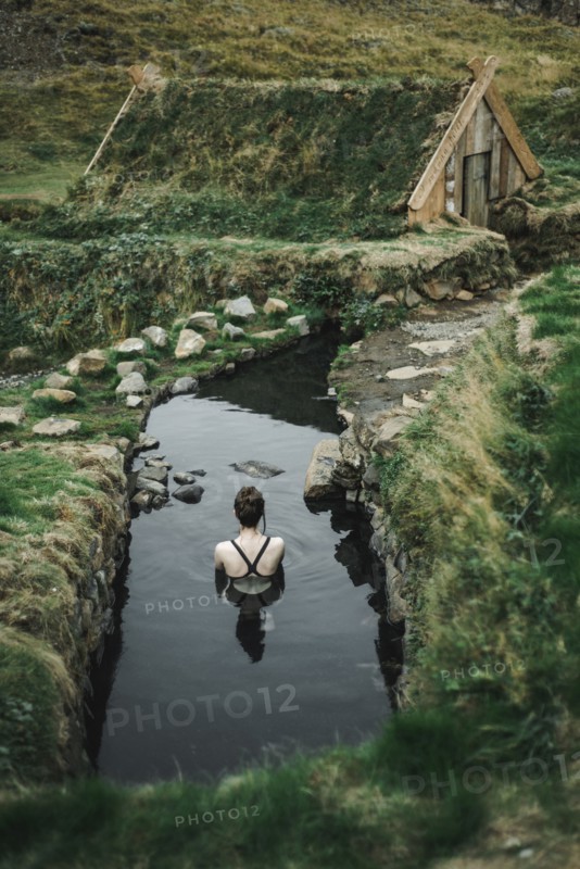 Caucasian woman swimming in pond near rural house