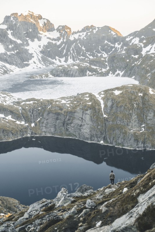 Caucasian man sitting on rock admiring scenic view of mountain lake