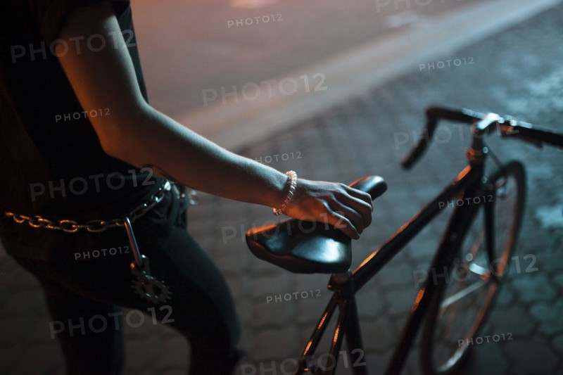 Caucasian man holding a bicycle seat at night