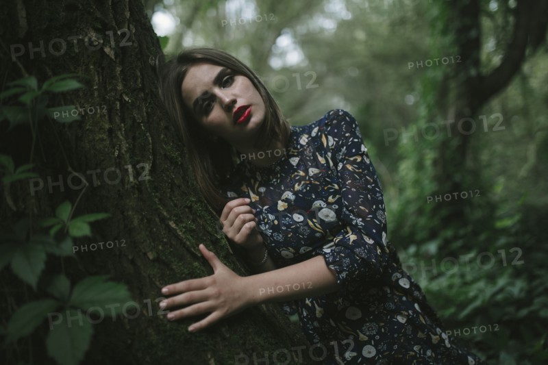 Caucasian woman leaning on tree trunk