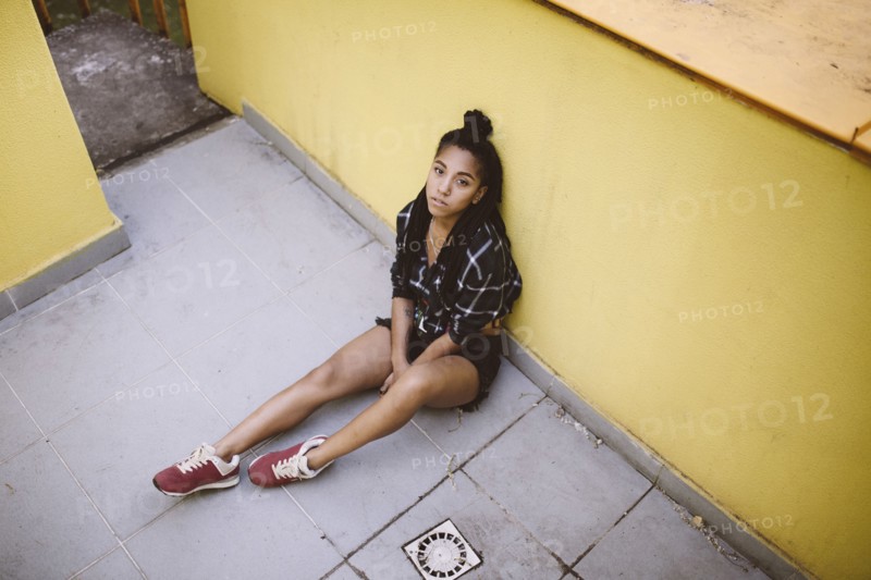 Portrait of serious African American woman sitting on sidewalk